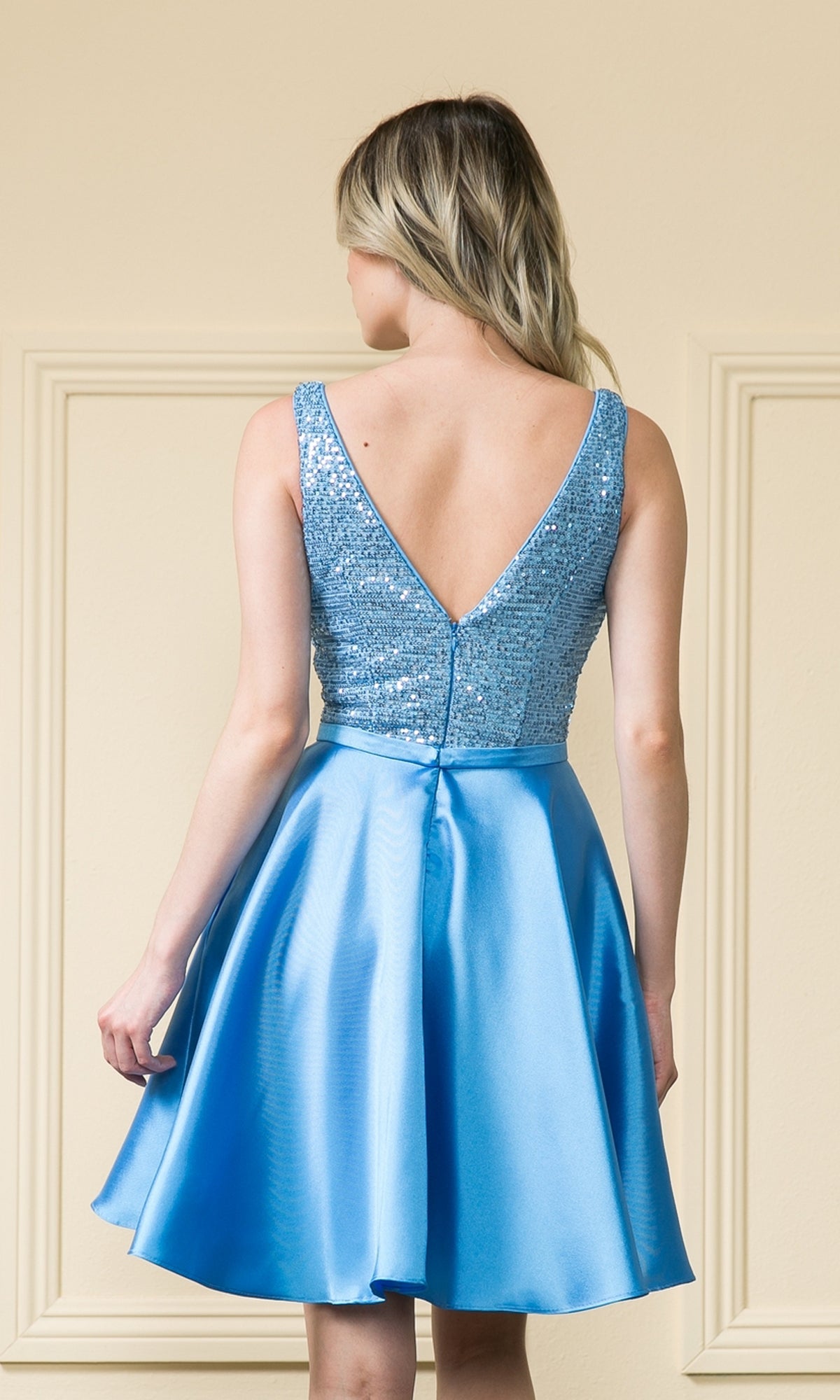 A woman faces away, wearing the A-Line Short Homecoming Dress with Pockets - 8954, featuring an embellished bodice and flared satin skirt in light blue.